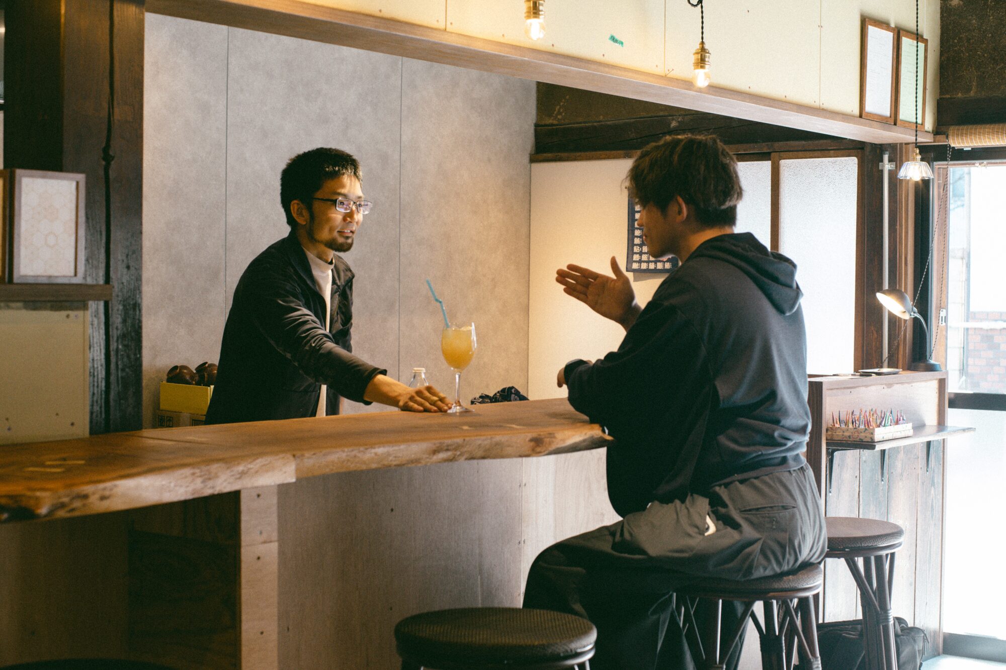 共用ラウンジのカウンターでスタッフと宿泊者が手話で会話する様子