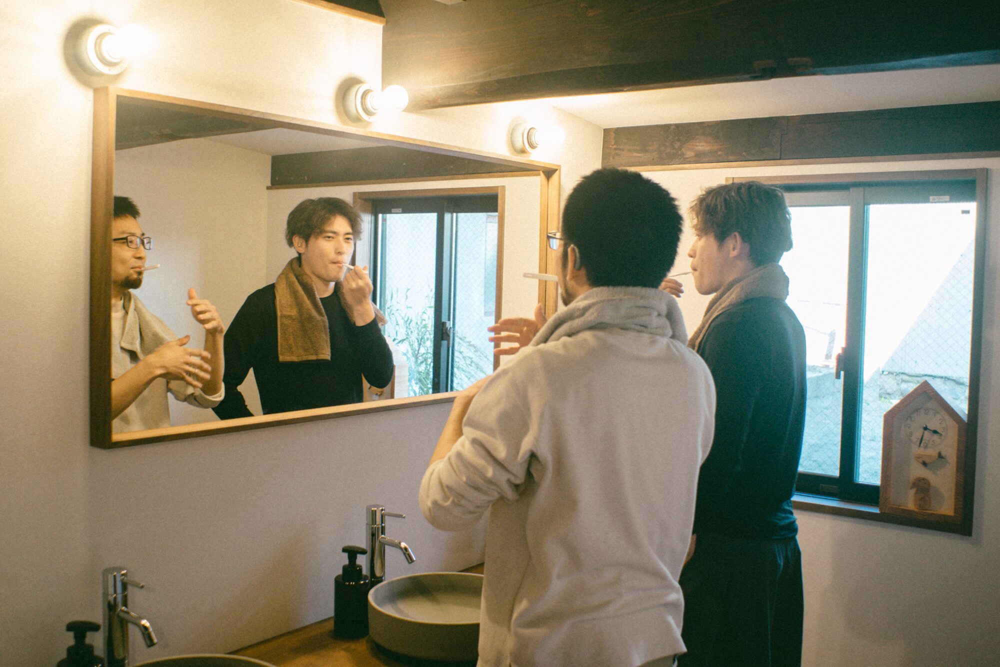 大きな鏡のある共用洗面スペースで身支度をする様子